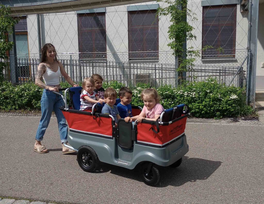 Frau schiebt mehrere Kinder mit Wagen