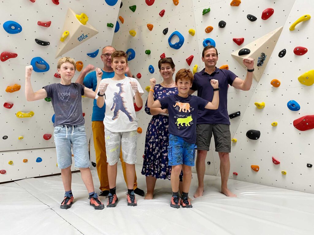 Kinder und Eltern stehen vor einer Kletterwand